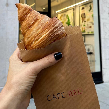 Croissant i brun brödpåse med tryckt logotyp "CAFE RED"