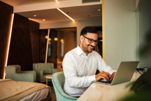 happy businessman using laptop in hotel room | Limepack happy businessman using laptop in hotel room