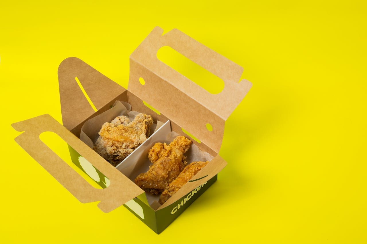 Box with takeaway food on yellow surface