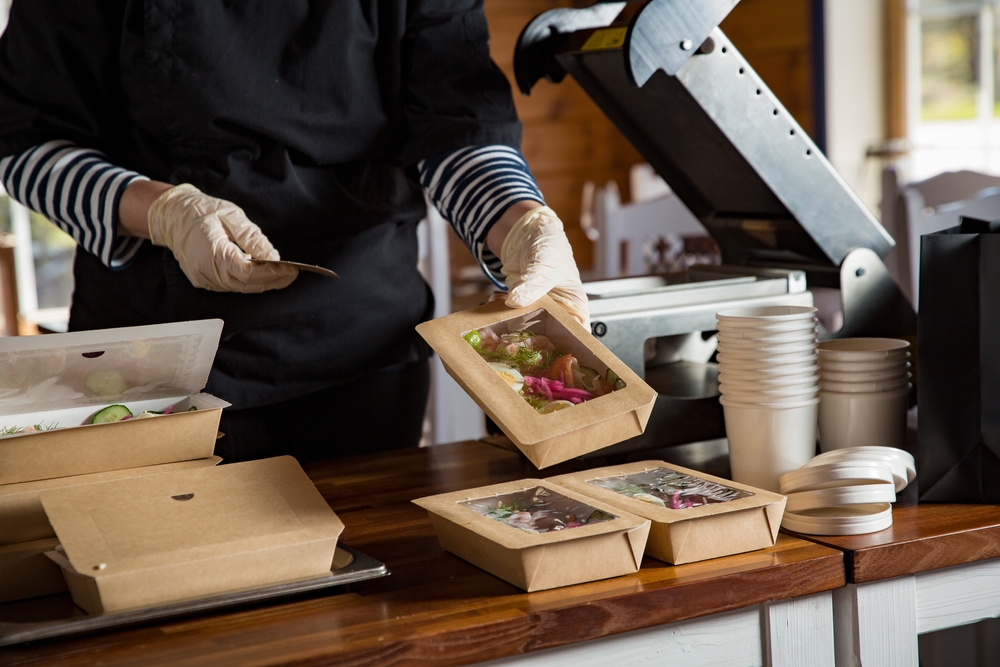 restaurant worker packaging food in takeaway boxes