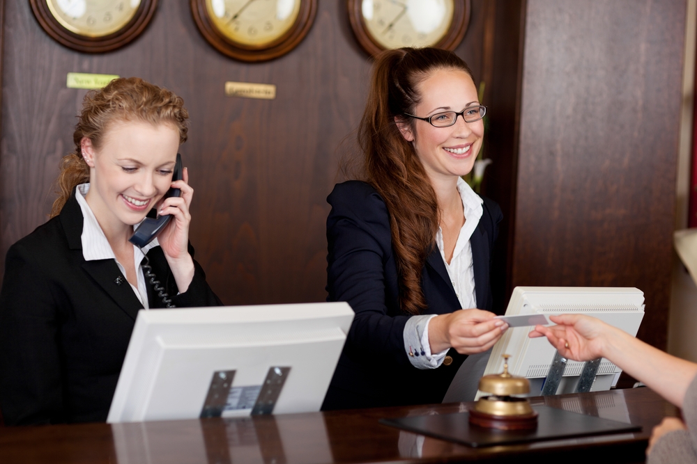 two hotel receptionists attending to guest