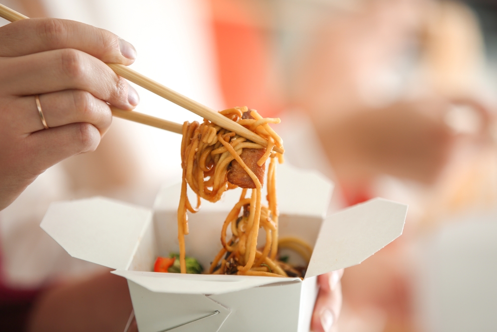 woman eating chinese noodles takeaway box