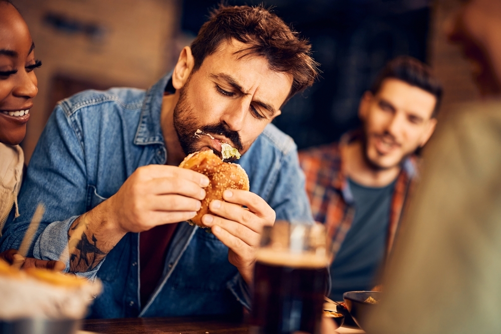 man eating burger with friends