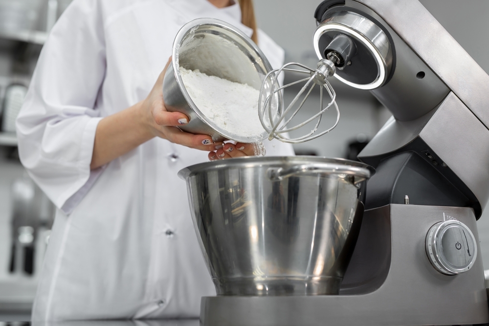 pastry chef adds flour in dough mixer