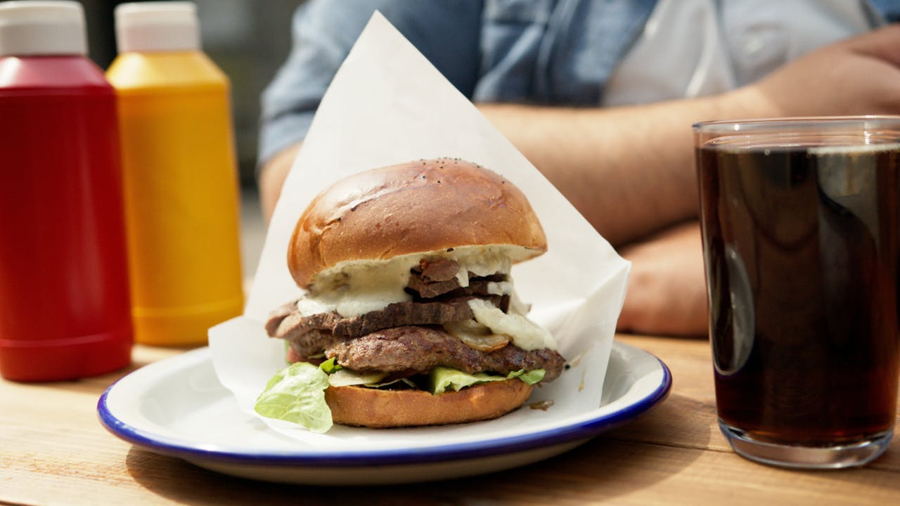 A Burger and Glass with Drink on the Table in a Restaurant