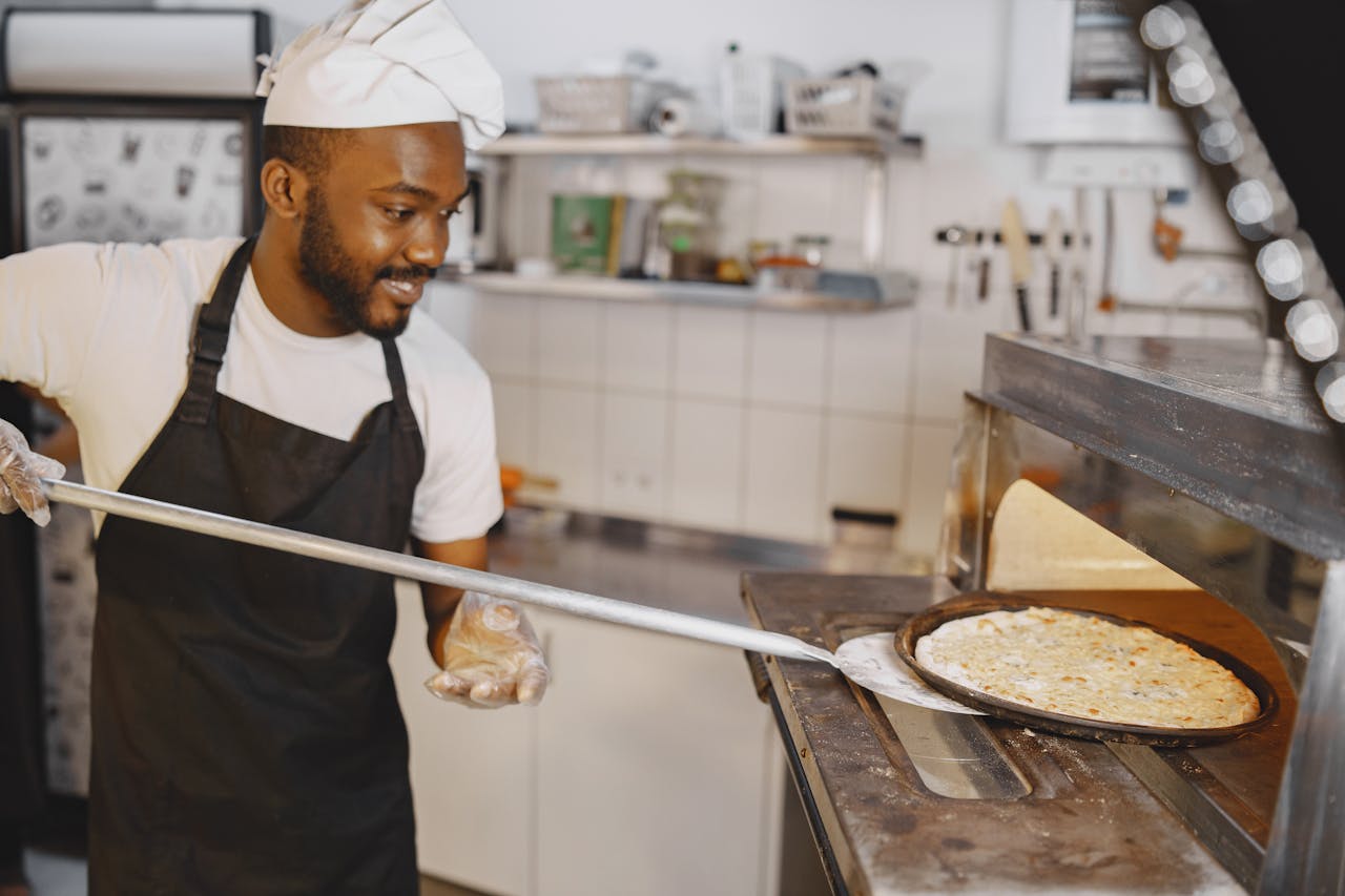 Cook Placing Pizza in Oven