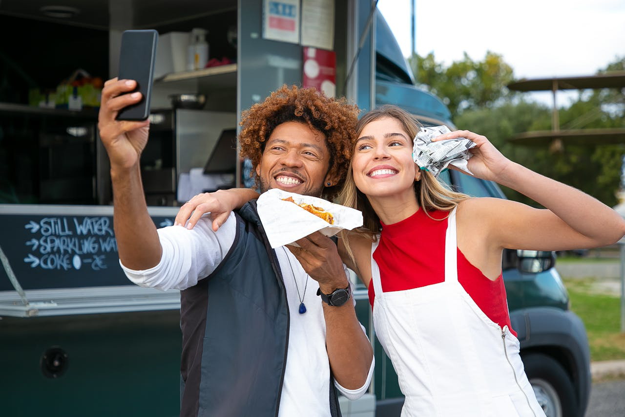 Happy friends with burgers taking selfie near food truck