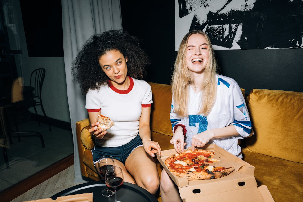 Women Eating and Getting a Slice of Pizza