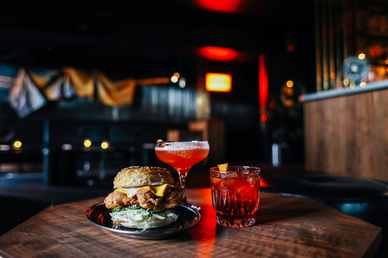 Delicious hamburger with cocktails on table