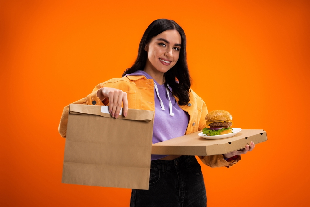 woman holding tasty burger and ecofriendly packaging