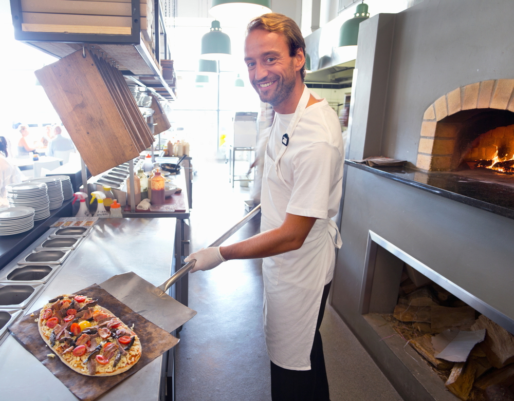 chef picking pizza from an oven