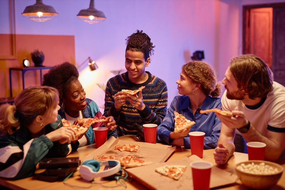 friends eating pizza and drinking alcohol in paper cups