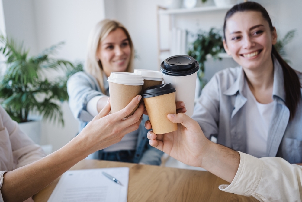group of friends holding up coffee cups celebrating