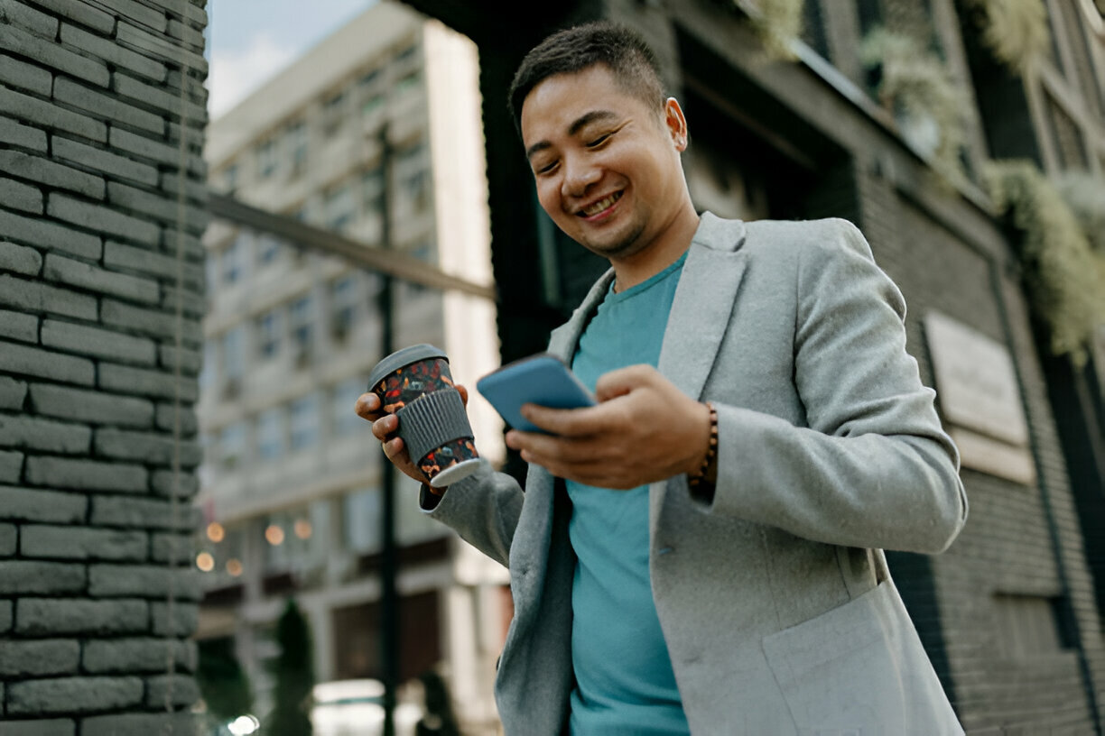 man using his mobile phone while drinking coffee