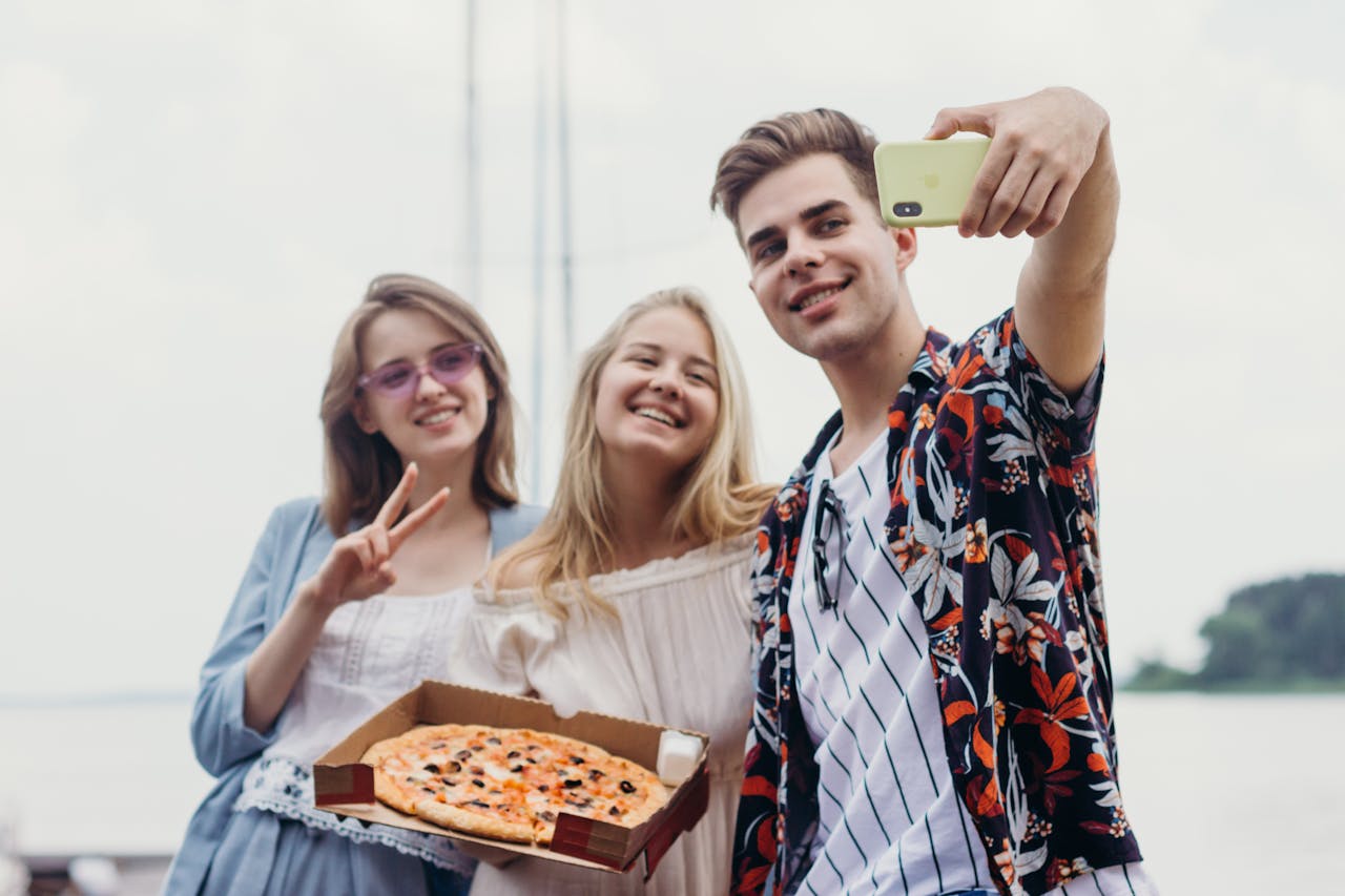 Friends With a Pizza Box Smiling Taking Selfie