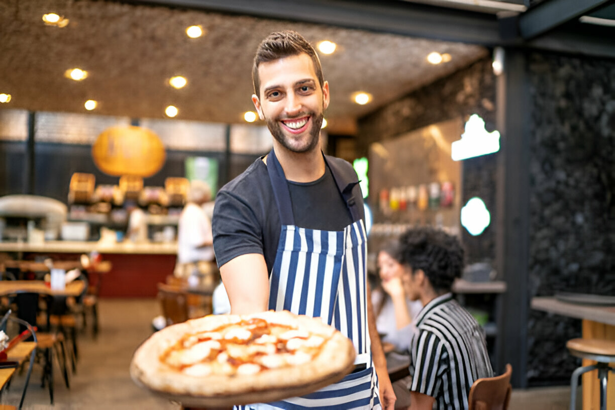 pizzeria shop chef holding a plate of pizza