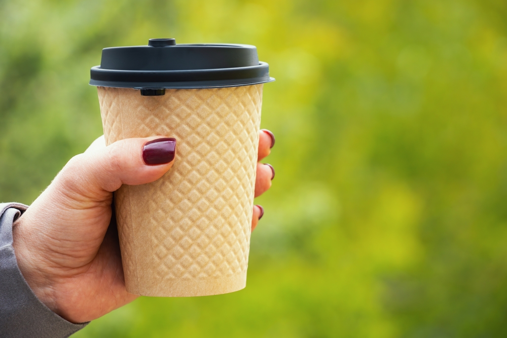 woman holding single use disposable coffee cup