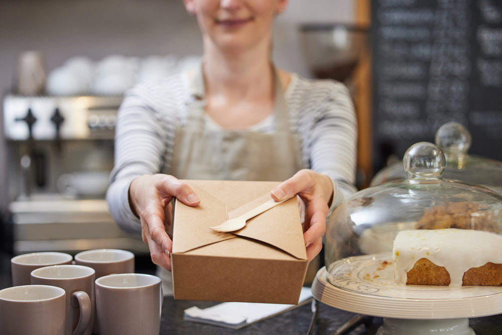 female worker serving takeaway food boxes