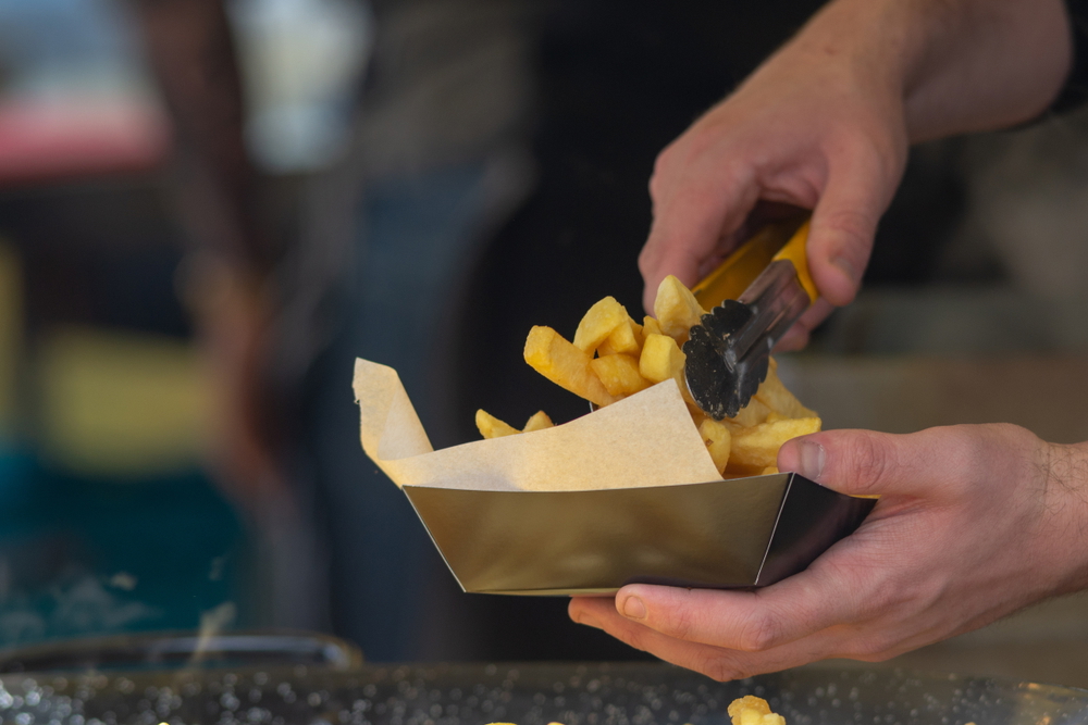 man serving fish and chips on a greaseproof paper