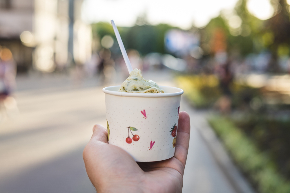 mans hand holds paper cup of ice cream